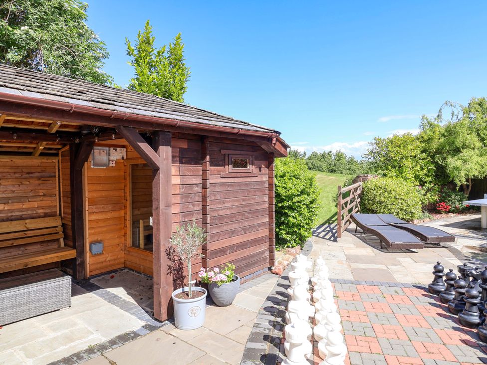 A backyard with a sauna, bench, and chess set at The Linhay in Washford near Watchet