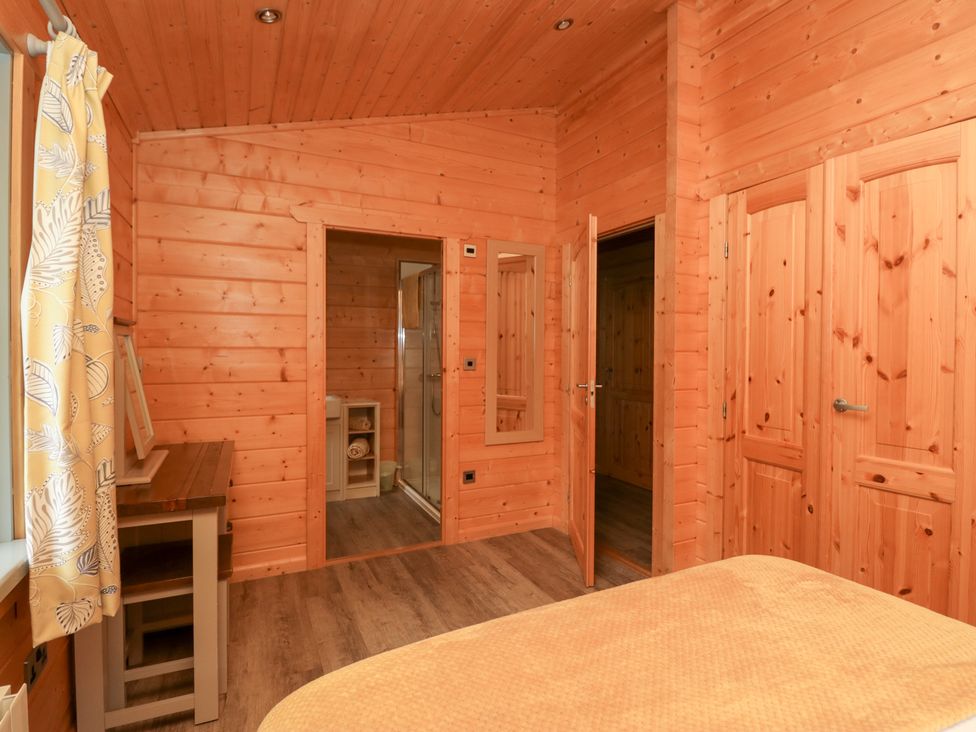 A bedroom with a bed and a table at Elm Lodge in Ulverston