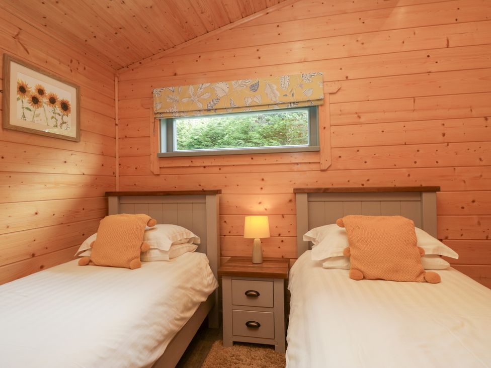 A bedroom with twin beds and a bedside table at Elm Lodge in Ulverston