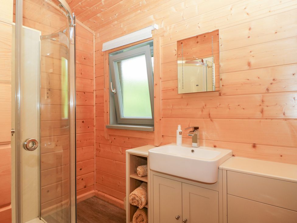 A bathroom with a shower, sink, and window at Elm Lodge in Ulverston