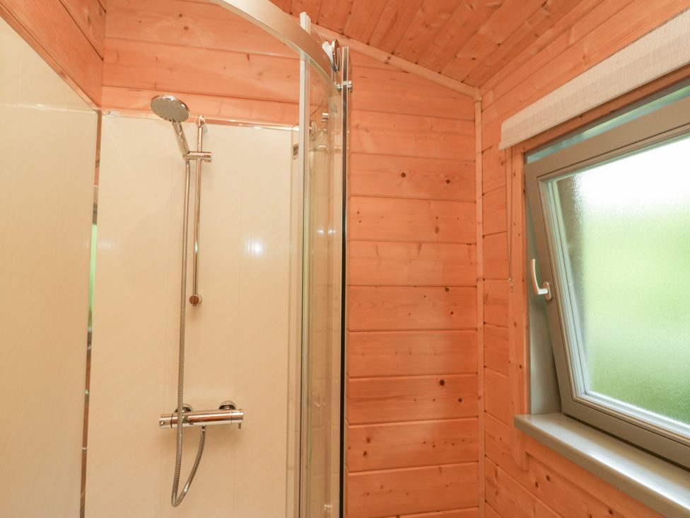 A shower with glass door and window at Elm Lodge in Ulverston