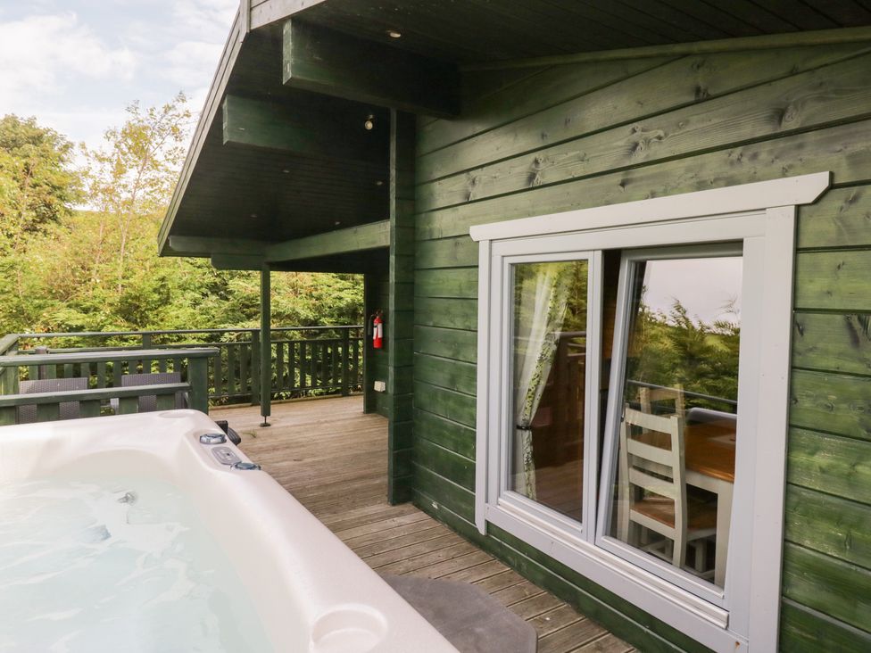 An outdoor area with a hot tub and a wooden deck at Elm Lodge in Ulverston