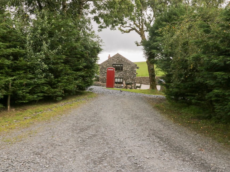 A gravel road leading to a stone building with a red telephone box at Elm Lodge in Ulverston