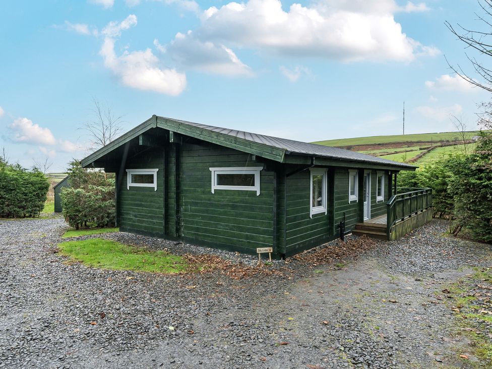 A cabin with a deck and gravel area at Elm Lodge in Ulverston