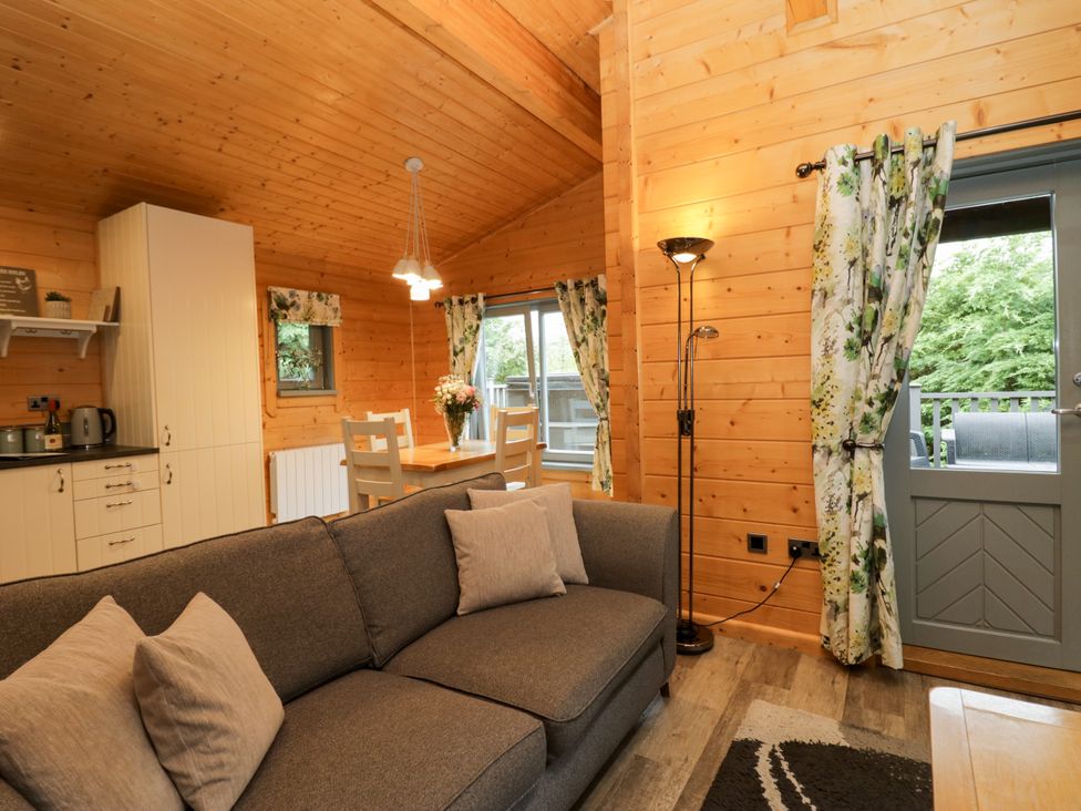A living room with a sofa and dining area at Elm Lodge in Ulverston