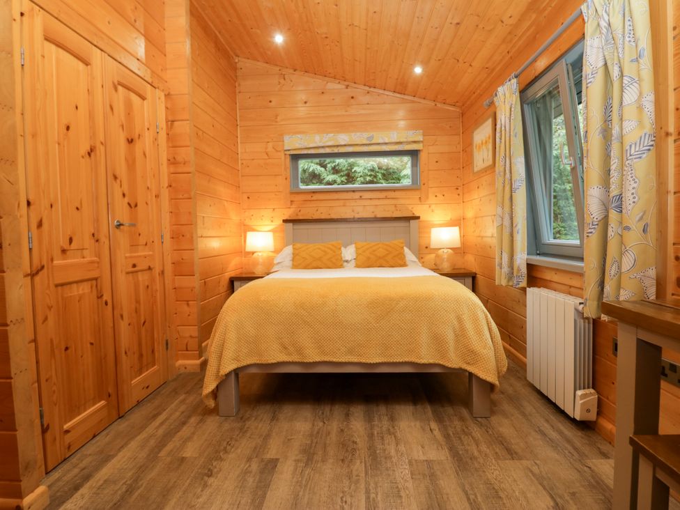 A bedroom with a bed and wardrobe at Elm Lodge in Ulverston
