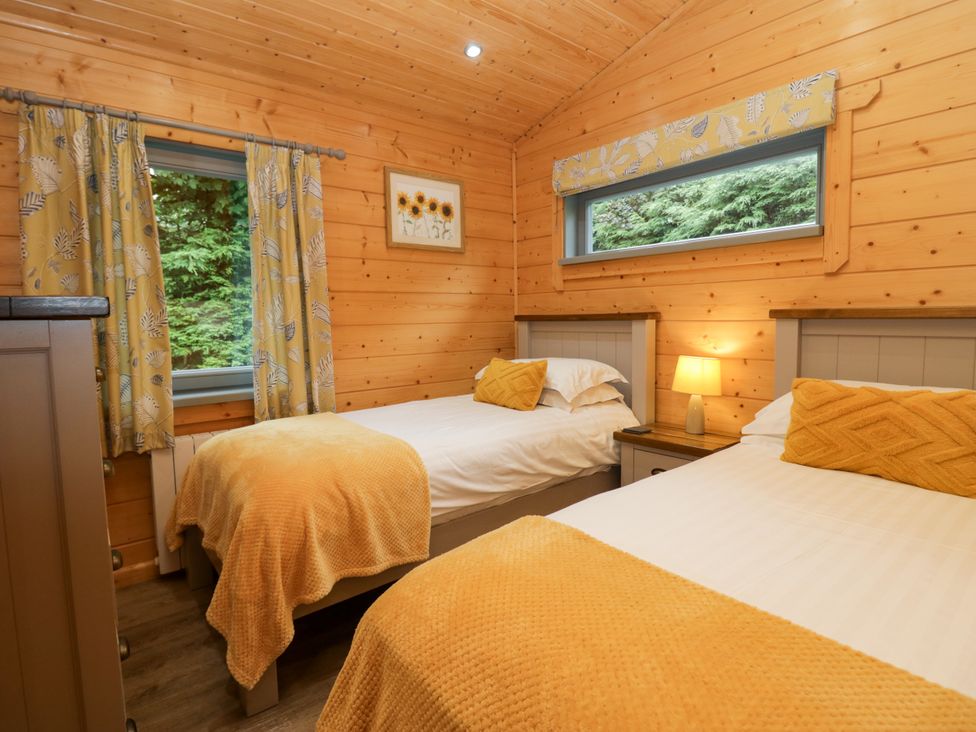 A bedroom with two beds and a lamp at Elm Lodge in Ulverston