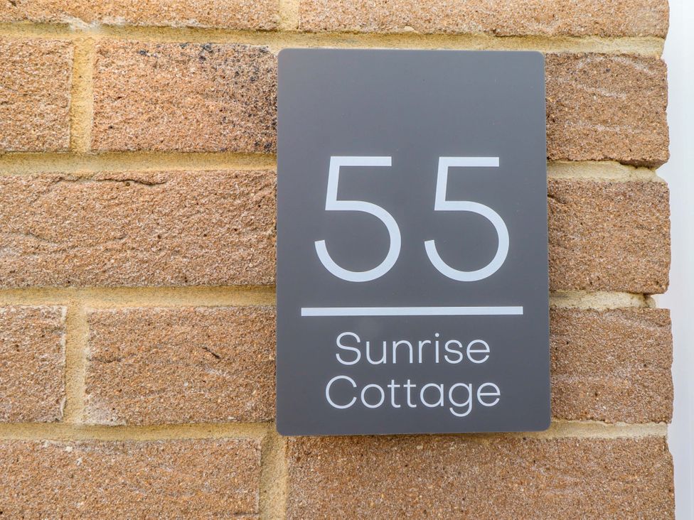 A house nameplate on a brick wall at Sunrise Cottage in Beadnell