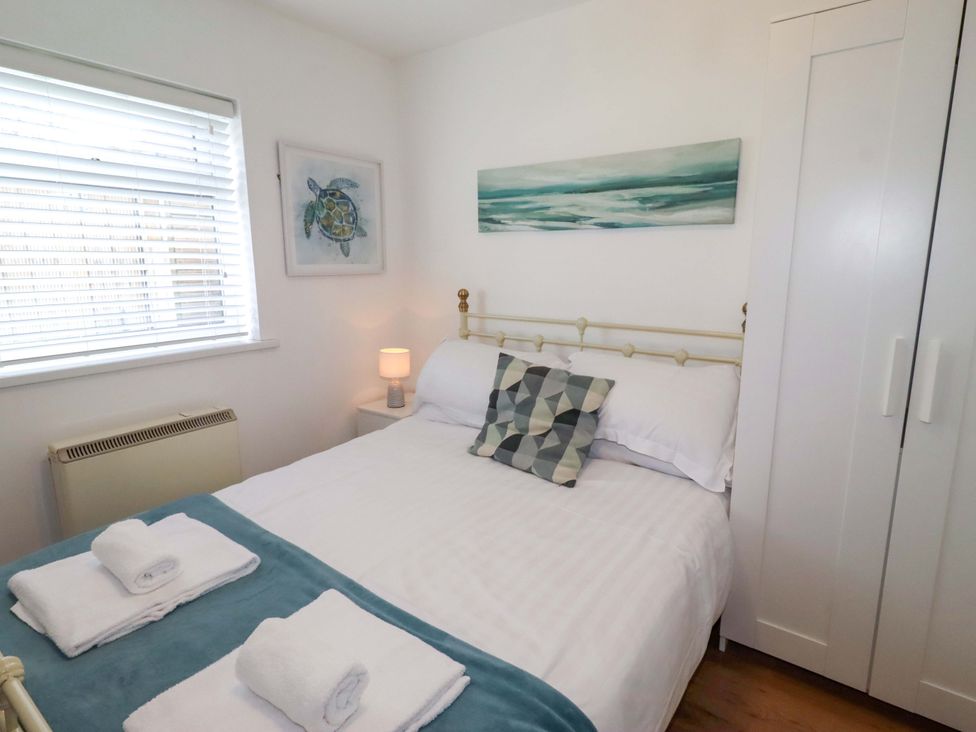 A bedroom with a bed and wardrobe at Sunrise Cottage in Beadnell