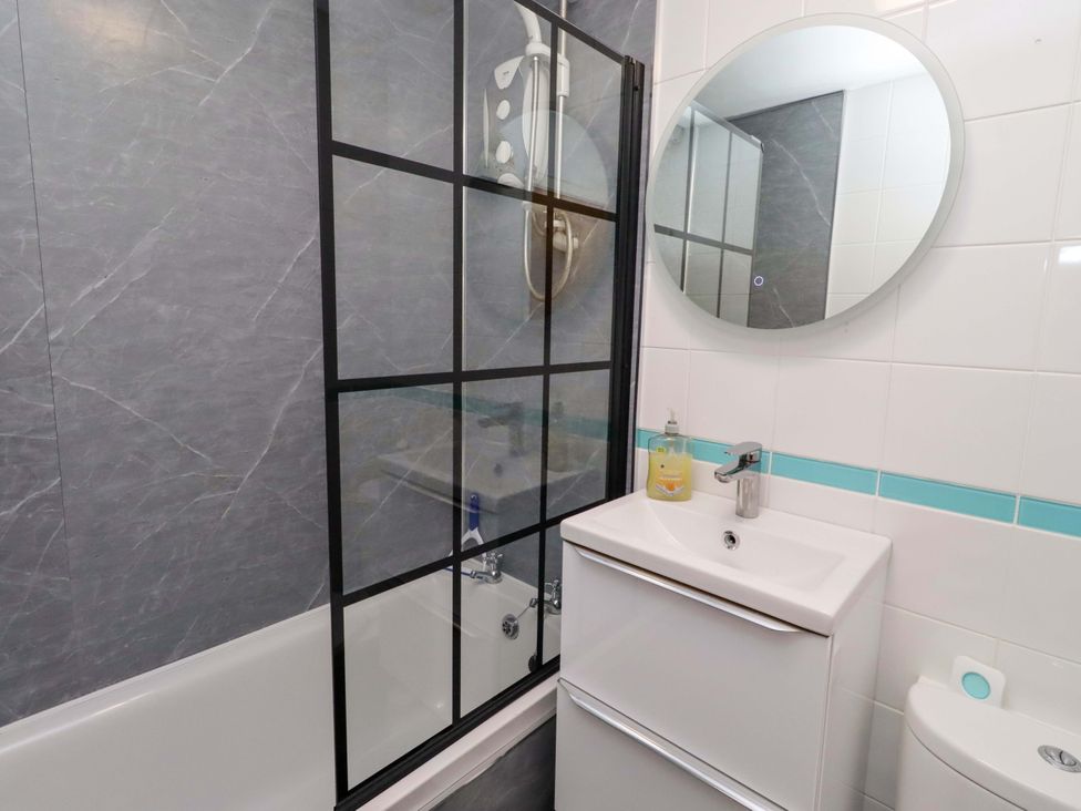 A bathroom with shower, bathtub, sink and toilet at Sunrise Cottage in Beadnell