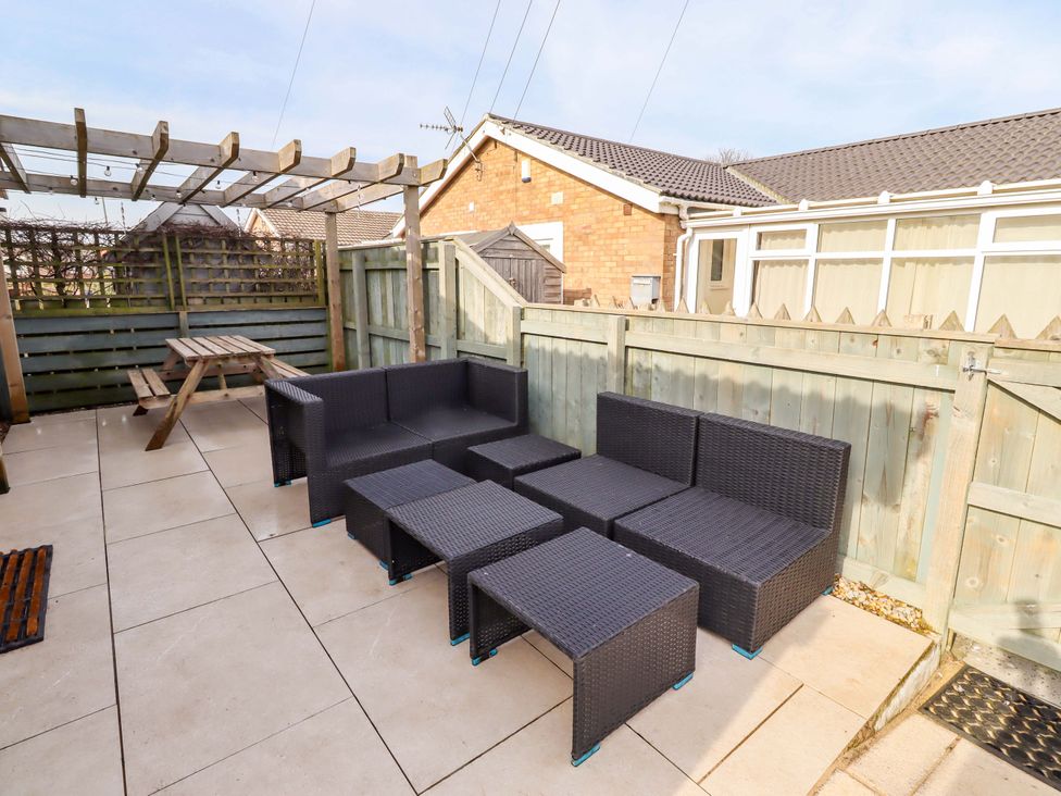 A garden patio with an outdoor seating set and a picnic table at Sunrise Cottage Beadnell