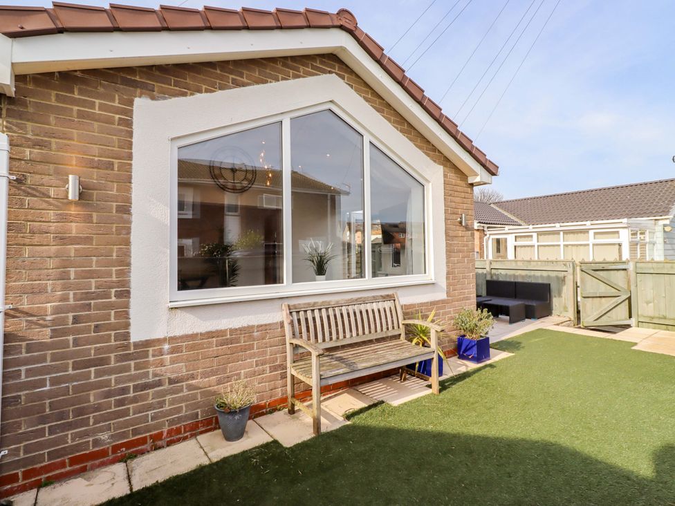 A garden with a bench and window at Sunrise Cottage in Beadnell