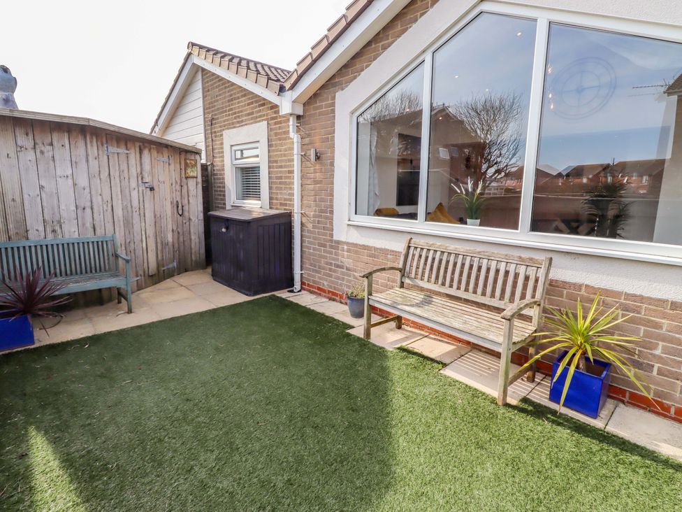 A garden with a bench and planter at Sunrise Cottage Beadnell