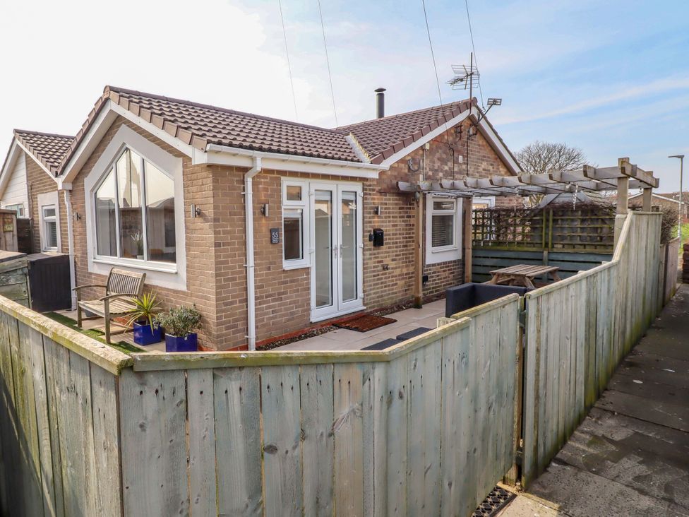 An outdoor view of a house with a patio and fence at Sunrise Cottage in Beadnell