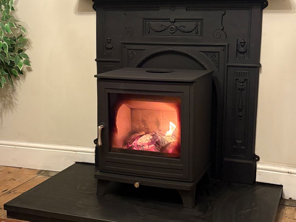 A stove with a fire in a fireplace at Haven in Porthleven