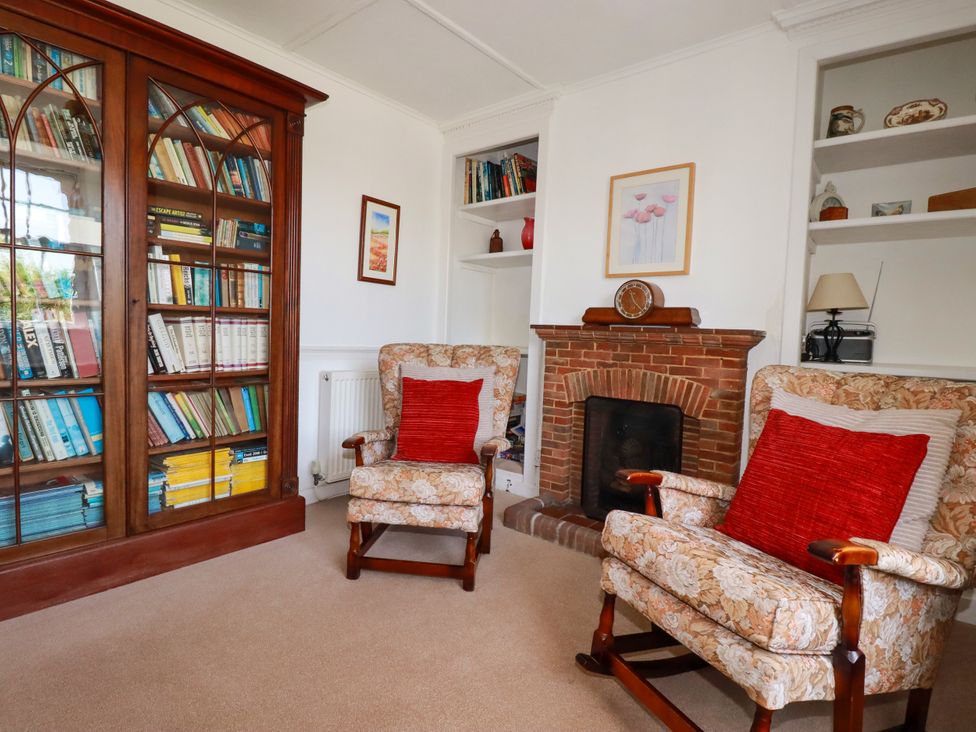 A living room with bookshelves and armchairs at Penrose Farm Cottage St Keverne