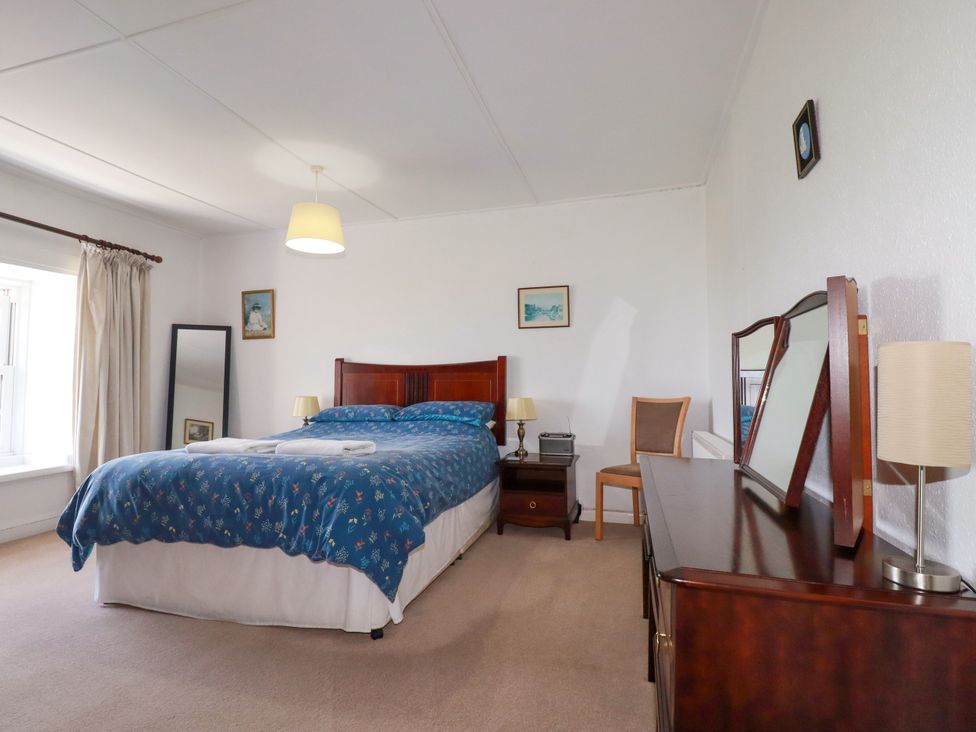 A bedroom with a bed and nightstand at Penrose Farm Cottage St Keverne