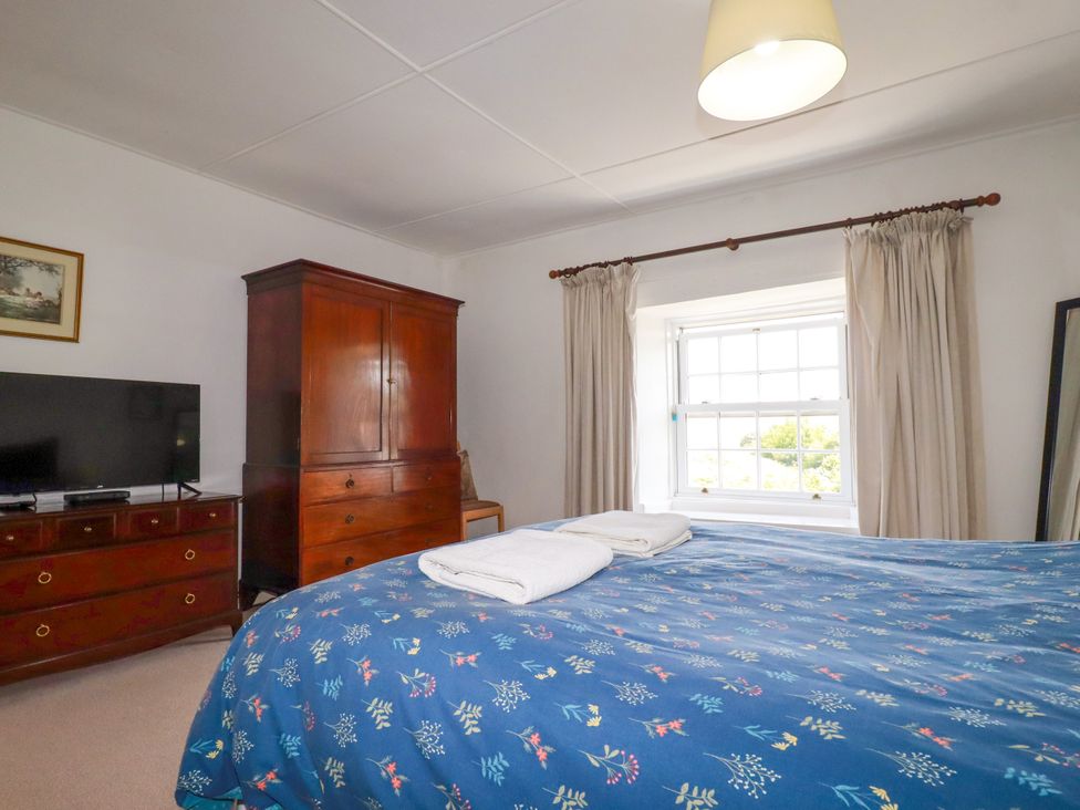 A bedroom with a bed, television, and wardrobe at Penrose Farm Cottage St Keverne