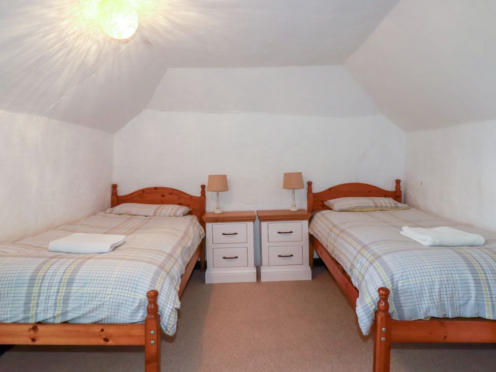 A bedroom with two beds and nightstands at Penrose Farm Cottage St Keverne