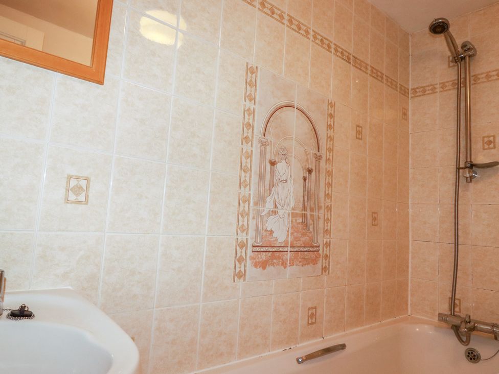 A bathroom with a bathtub and shower fixtures at Penrose Farm Cottage St Keverne