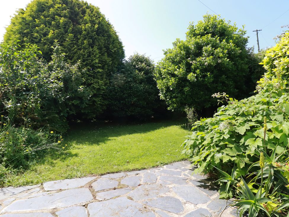 A garden with a stone path and shrubs at Penrose Farm Cottage St Keverne