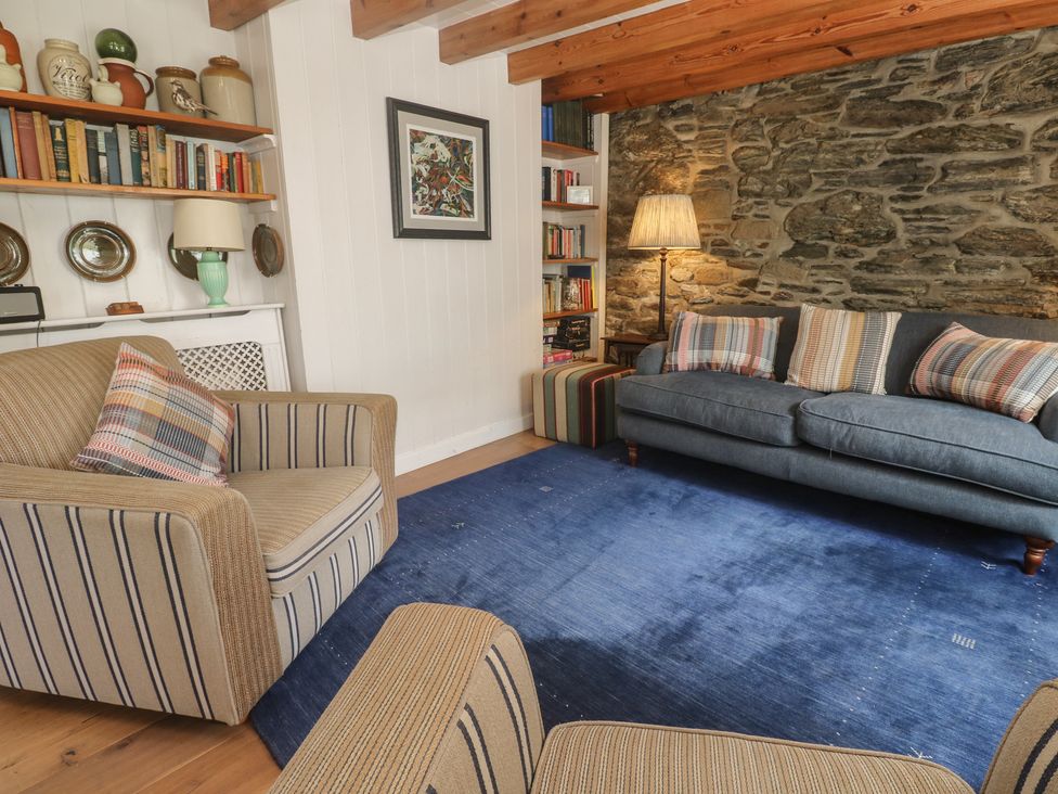 A living room with a bookshelf and seating at Pegs in Porthleven