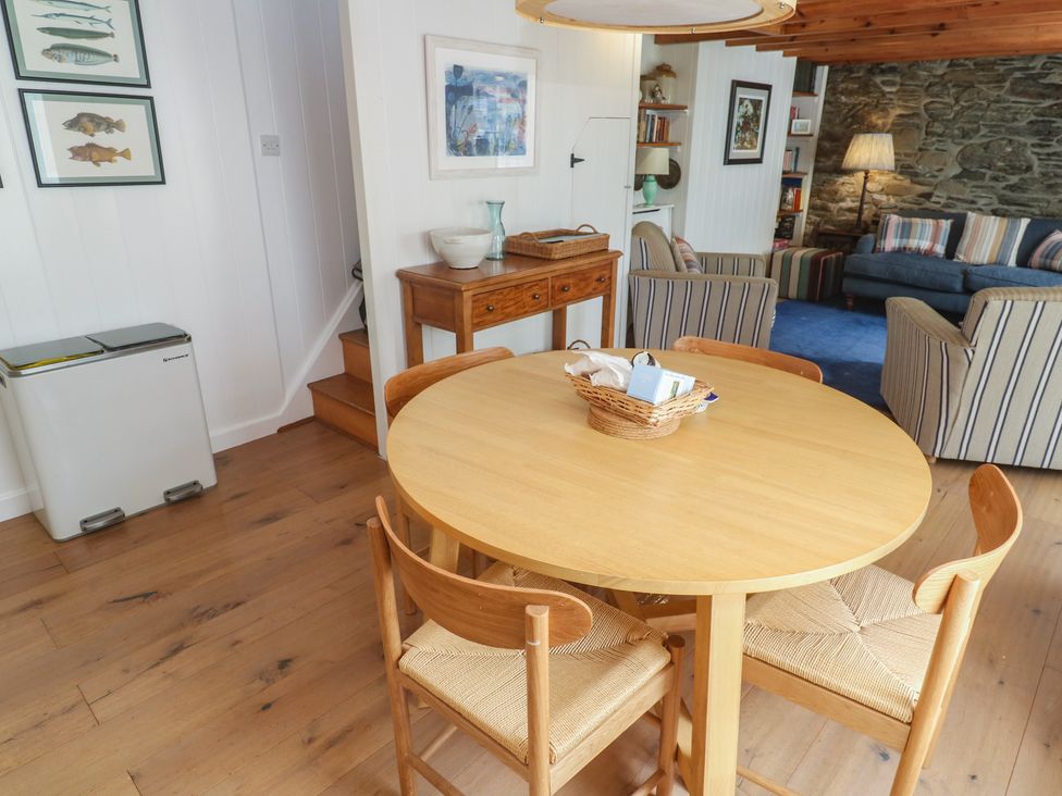 A dining room with a round table and framed pictures at Pegs in Porthleven