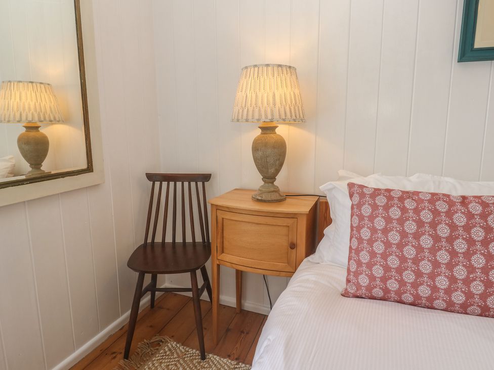 A bedroom corner with a lamp, chair, and nightstand at Pegs in Porthleven