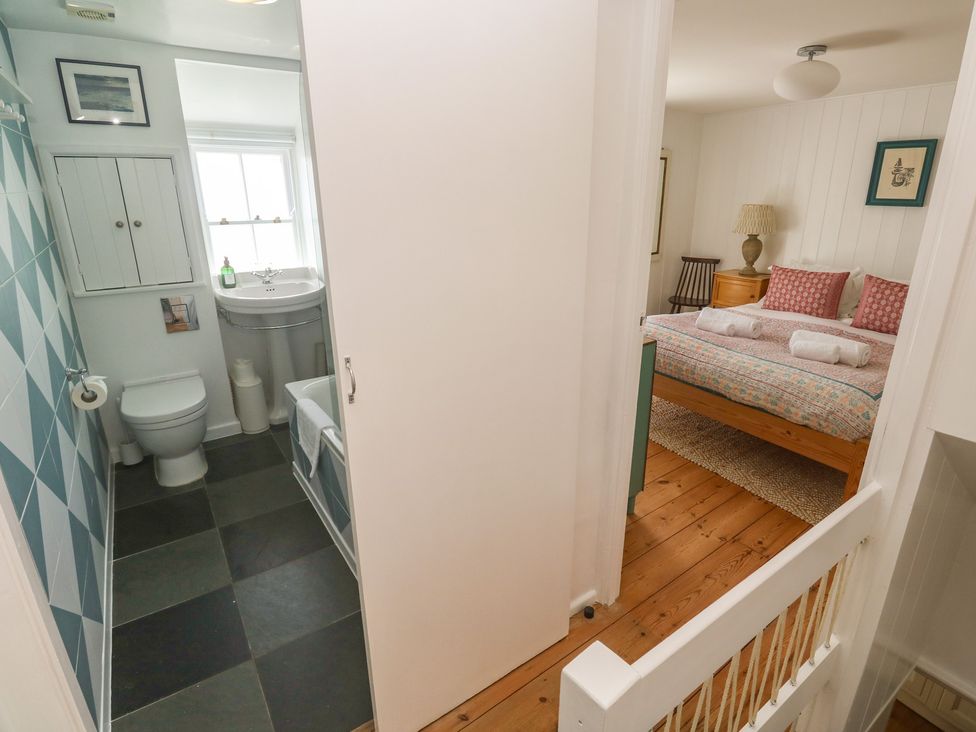 A bathroom with toilet and sink viewed from a hallway at Pegs in Porthleven