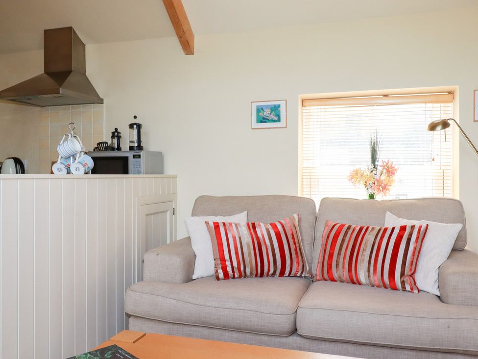 A living room with a sofa and kitchen appliances at Mithian Cottage in St Agnes