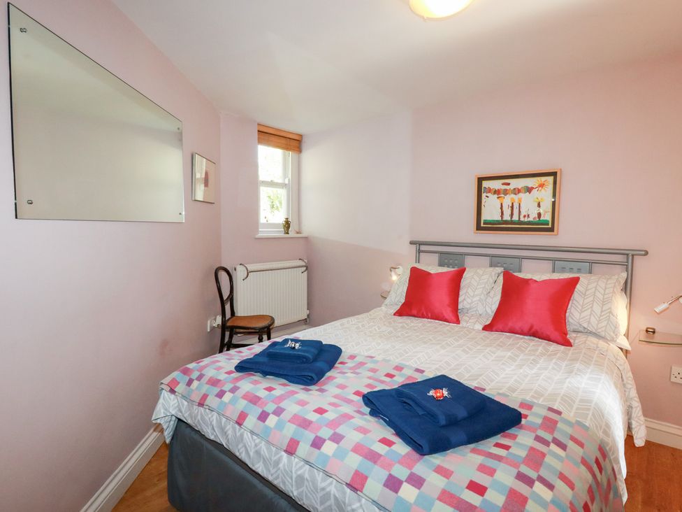 A bedroom with a bed and chair at Mithian Cottage in St Agnes