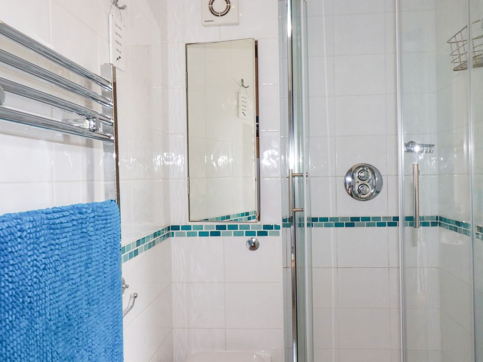 A bathroom with a shower enclosure and a blue towel at Mithian Cottage in St Agnes
