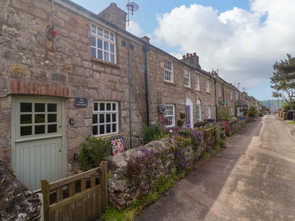 A cottage facade with a sign at May Cottage in Pentewan