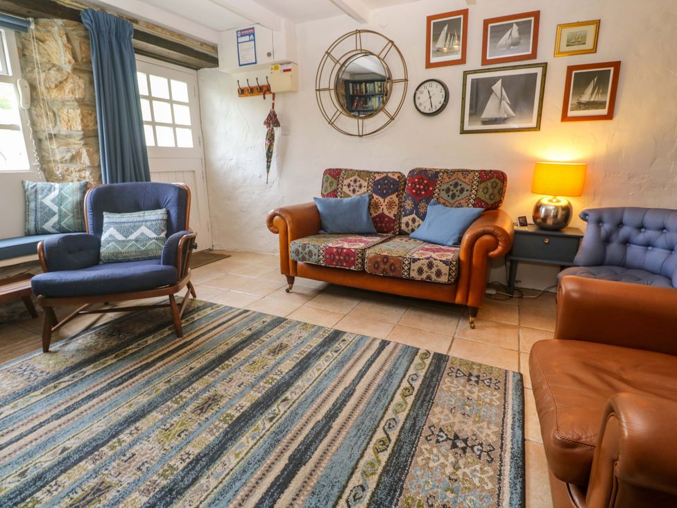 A living room with a sofa and armchair at May Cottage in Pentewan