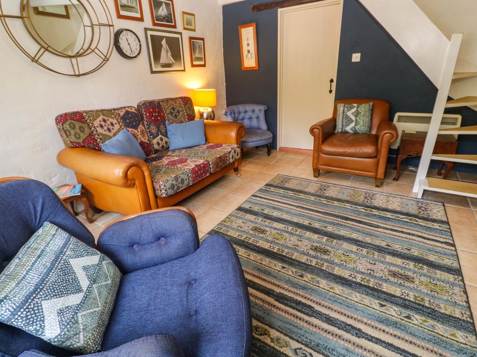 A living room with a sofa, armchair, and rug at May Cottage in Pentewan