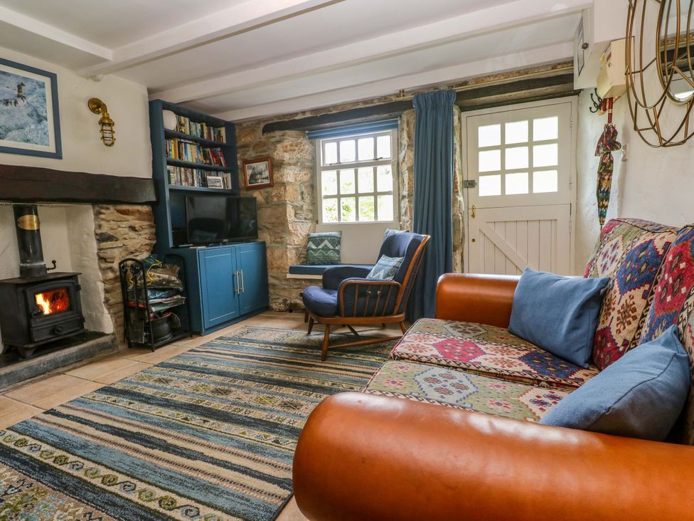 A living room with a fireplace and sofa at May Cottage in Pentewan