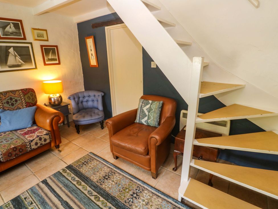 A living room with a staircase and seating area at May Cottage in Pentewan