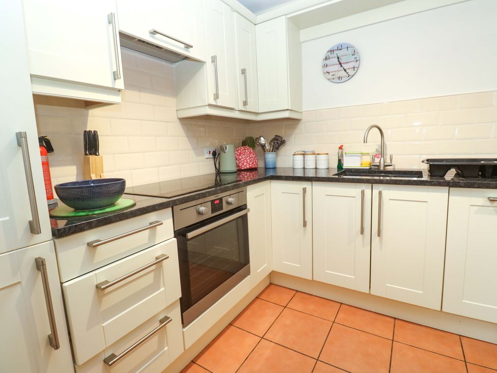 A kitchen with cabinets, an oven, and a sink at May Cottage in Pentewan