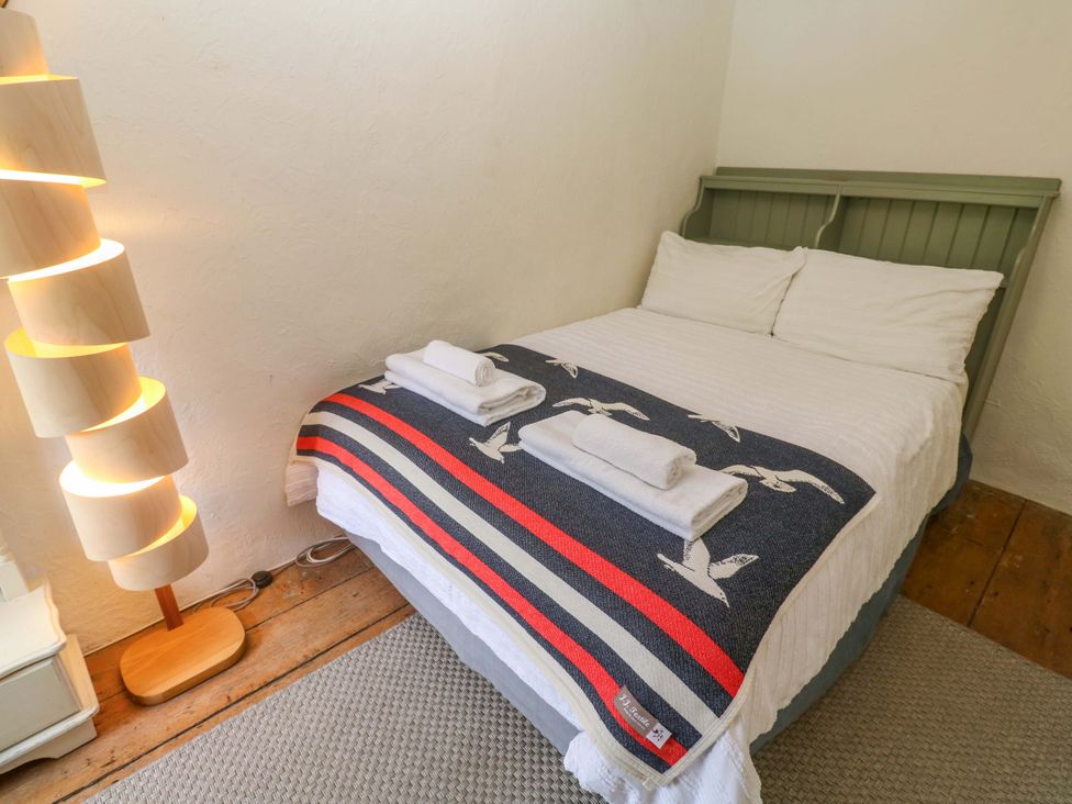 A bedroom with a bed, lamp, and towels at May Cottage in Pentewan