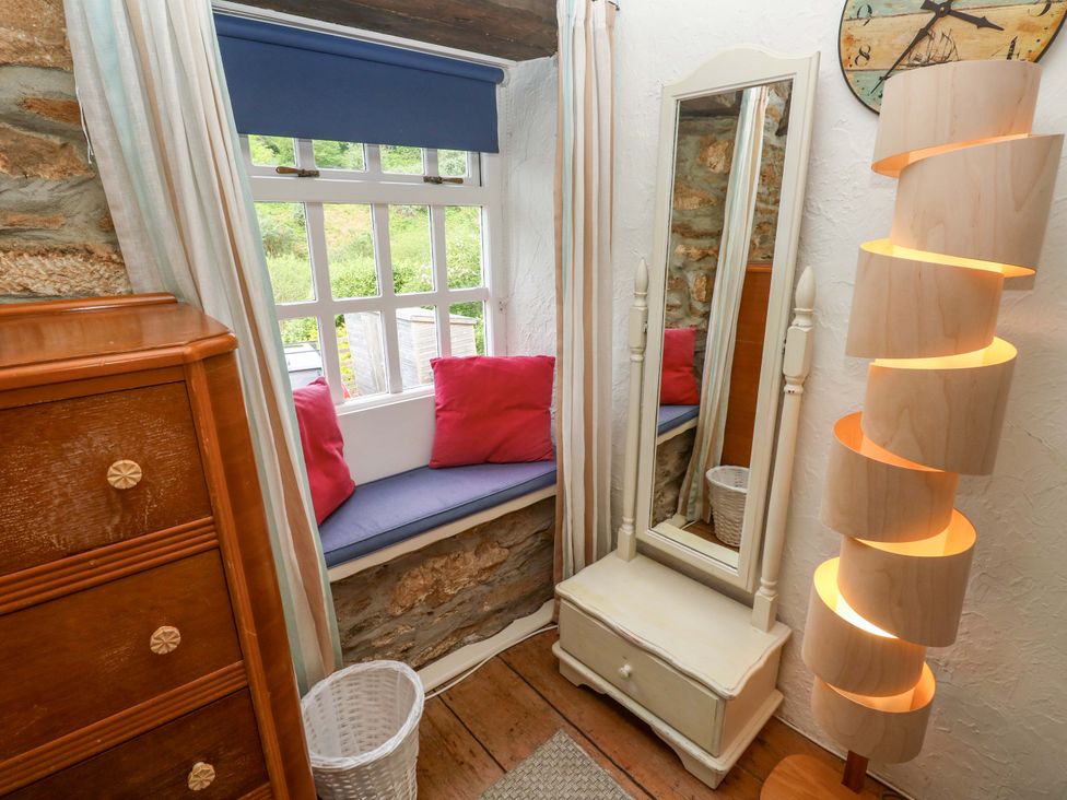A bedroom with a window seat and a full-length mirror at May Cottage Pentewan