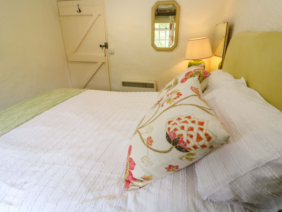 A bedroom with a bed and lamp at May Cottage in Pentewan