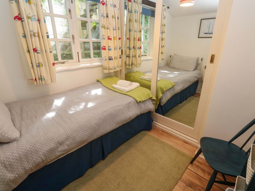 A bedroom with two beds and a mirror at May Cottage in Pentewan