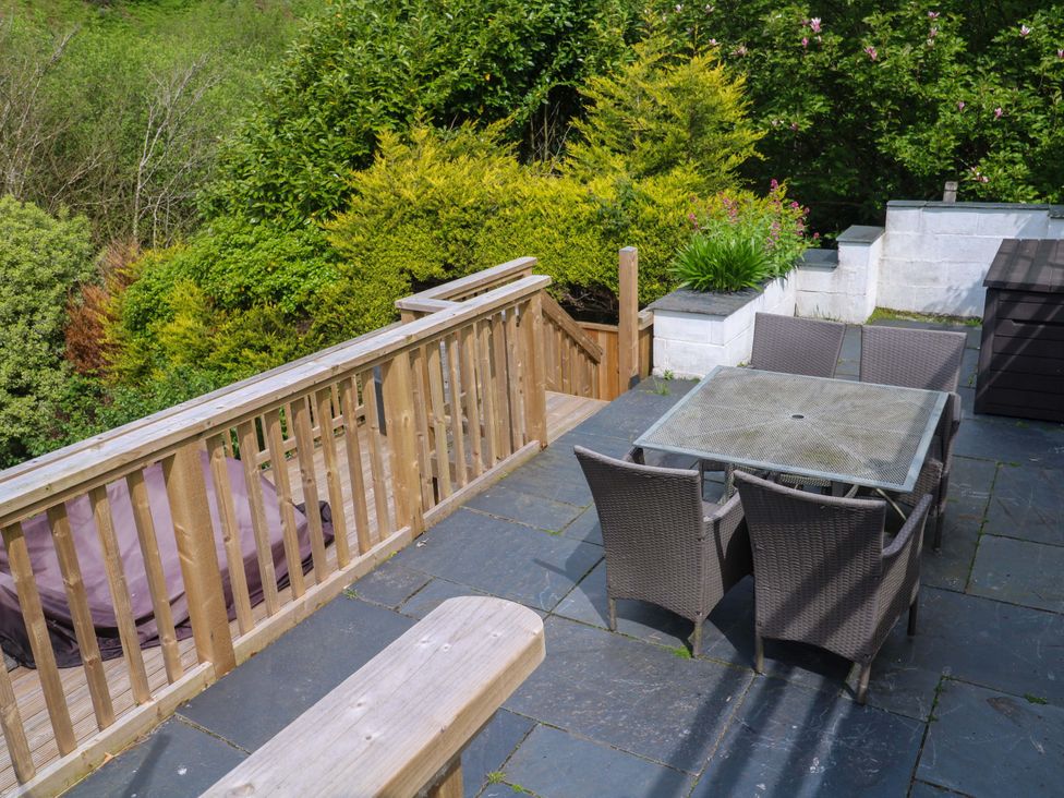 A garden with a table and chairs on decking at May Cottage in Pentewan