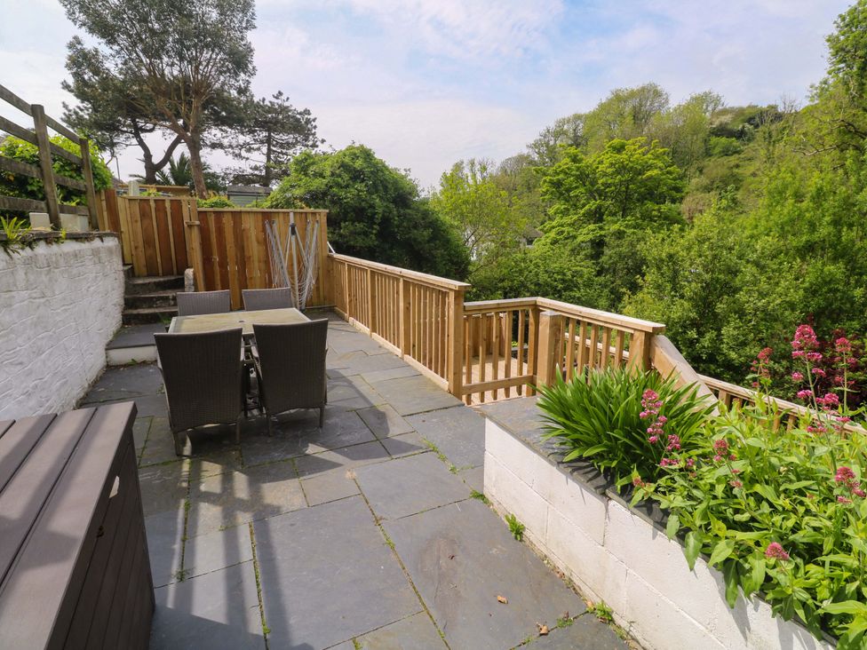 A garden with outdoor seating and a wooden fence at May Cottage in Pentewan