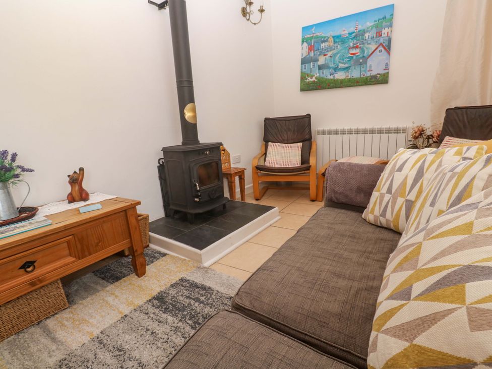 A living room with a stove and sofa at Godrevy Cottage in Hayle
