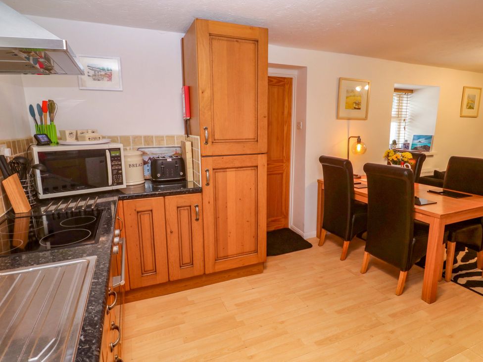 A kitchen with appliances and dining area at Godrevy Cottage in Hayle