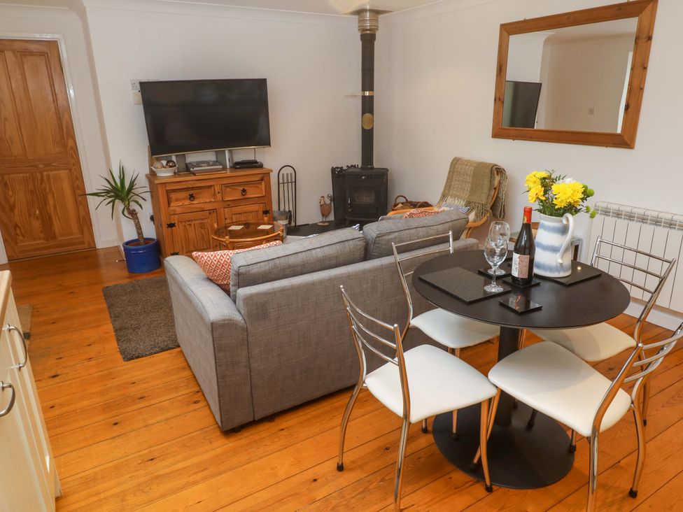 A living room with a sofa, dining table, and television at Godrevy Barn in Hayle