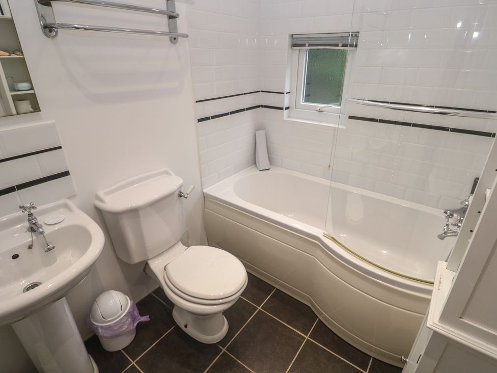 A bathroom with a shower over a bathtub and sink at Banneth in Helford