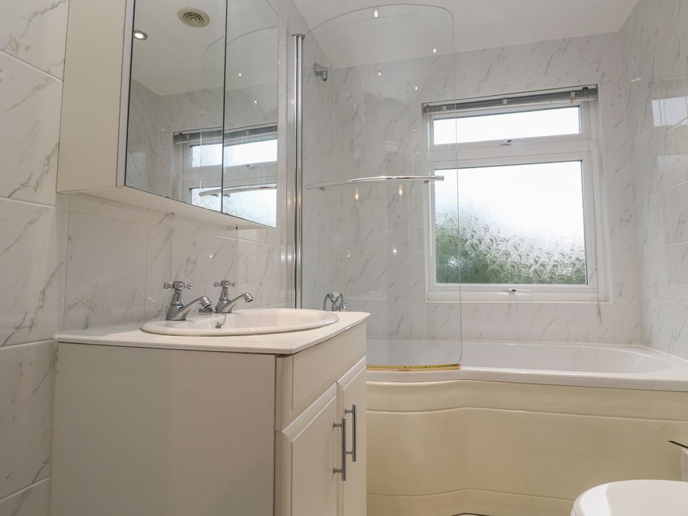 A bathroom with a sink, mirror, shower, and bathtub at Banneth Helford