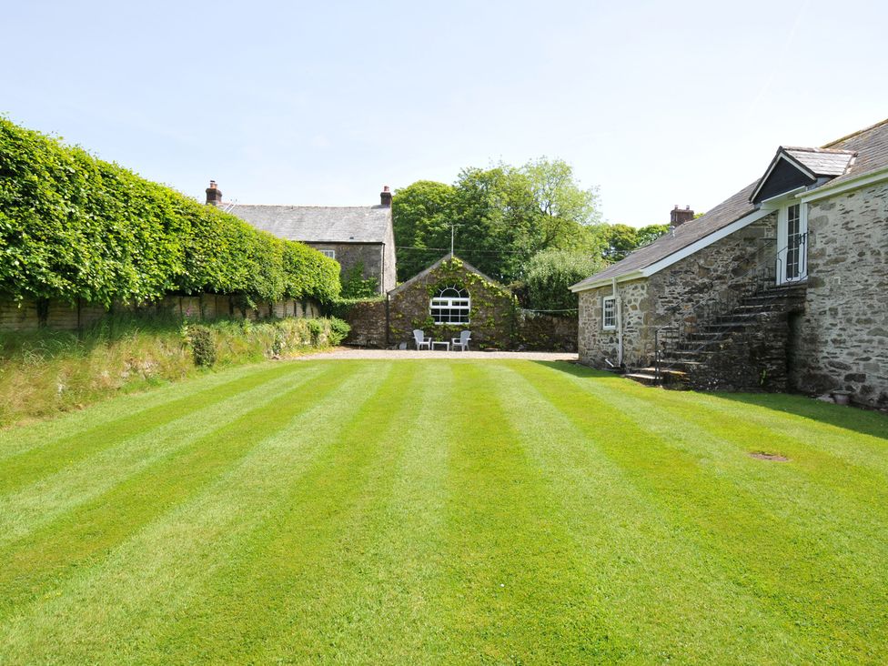 A garden with grass and buildings at Trevenning Chapel Near Port Isaac